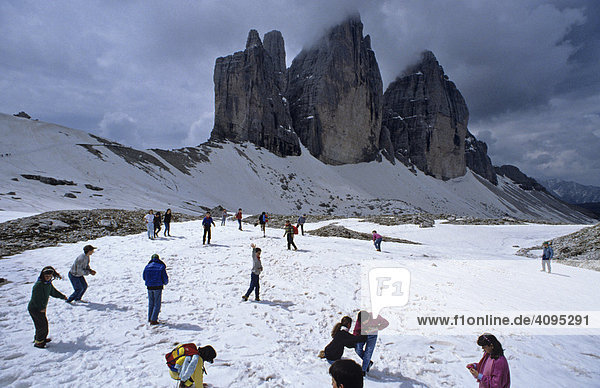 Pupils on snow field in front of summit of Drei Zinnen in Dolomites near Sexten Italy