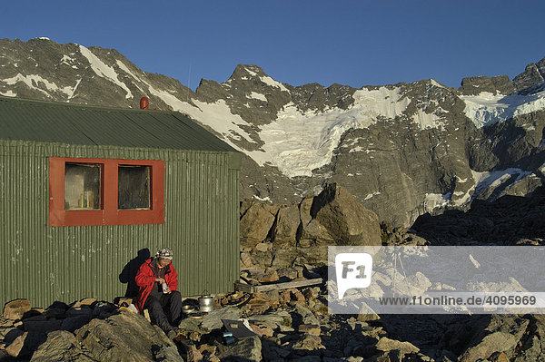 Hiker sits in the evening sun at the old Mueller hut  Mount Cook Nationalpark  South Island  New Zealand
