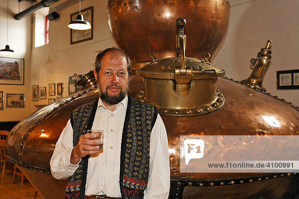 Mann mit Glas Whiskey und alte Kupferblase zum Destillieren des Alkohols in der Bushmills Whiskey Distillerie  Bushmills  Londonderry  Nordirland