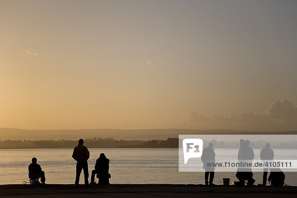 Silhouetten von Personen im Hafen von Syrakus  Sizilien  Italien