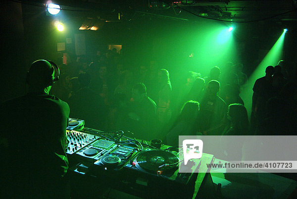 Club DJ playing a set in a crowded nightclub