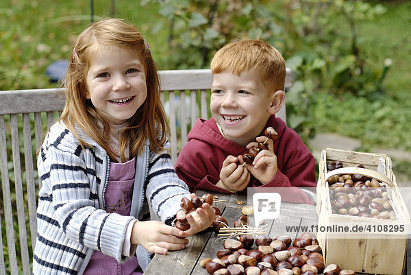 Children making crafts out of chestnuts in autumn