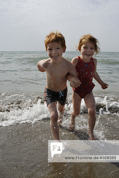 Zwei Kinder laufen am Strand entlang