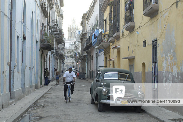 Oldtimer und Fahrradfahrer in einer Gasse in der Altstadt Havanna  Kuba  Karibik