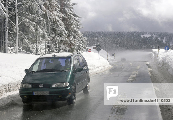 Auto auf der Gegenfahrbahn im Wald auf der nassen Straße durch das Erzgebirge im Winter  Sachsen  Deutschland