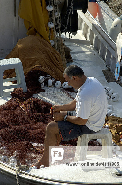 Fisherman repairing nets on his boat  Porto Christo  Majorca  Balearic Islands  Spain