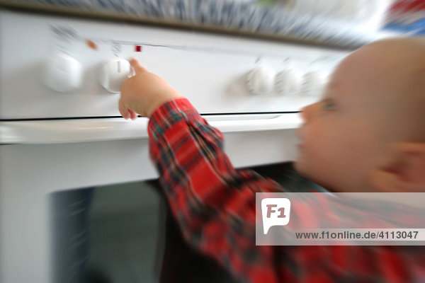Little child plays with the stove