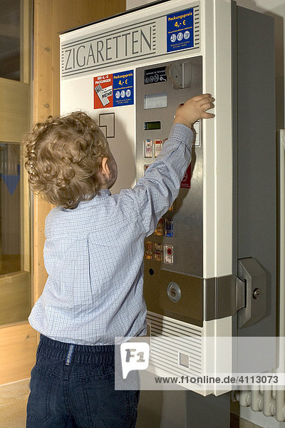 Little boy plays with a cigarette machine