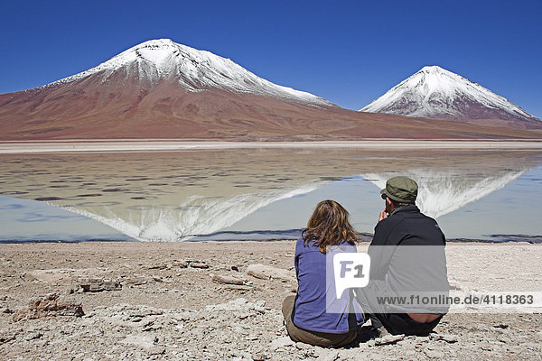 Man and woman  Laguna Verde and Licancabur volcano on the right  Bolivia near the border to Chile  South America