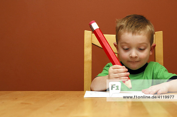 Boy writing with a big pencil