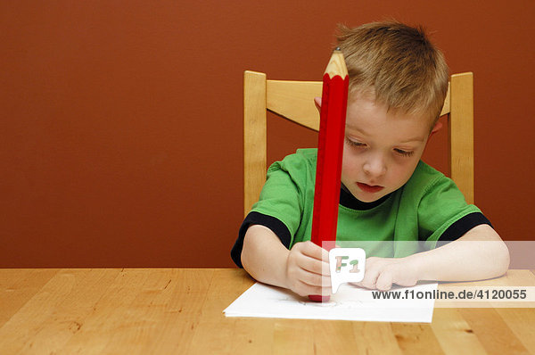 Young boy (age 5) erasing with a huge pencil