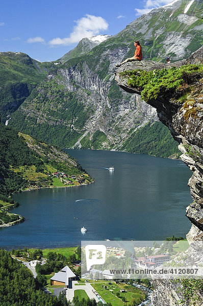 Frau sitzt auf einem Felsvorsprung  Geirangerfjord  Norwegen  Skandinavien