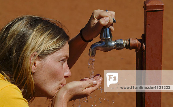 Frau trinkt klares Wasser aus einem Wasserhahn in der australischen Wüste  Outback  Australien