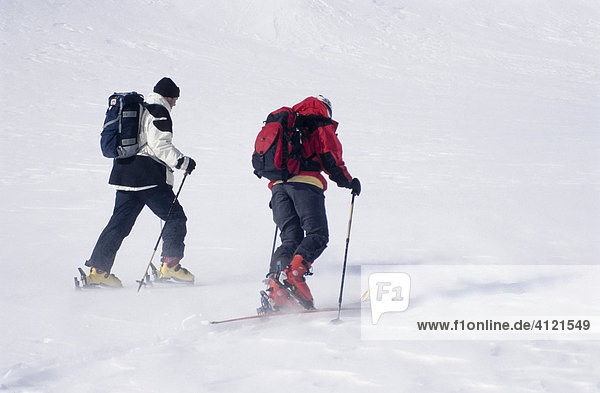 Two ski tourers  skiers carrying backpacks  snow flurry