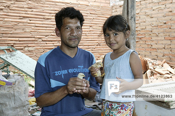 Guarani father and daughter with fledgling in his hand  in the poor area of Chacarita  Asuncion  Paraguay  South America