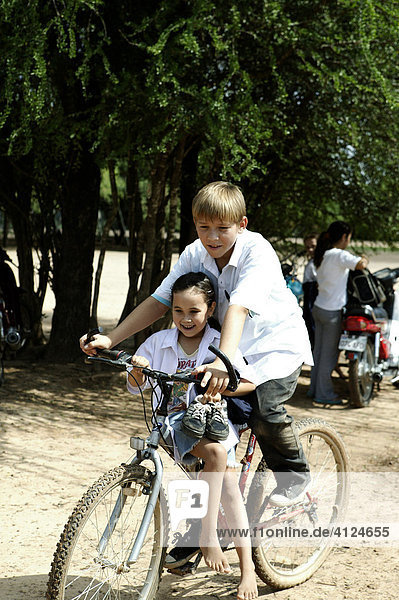 Brother picking up his little sister from school with bicycle  Loma Plata  Chaco  Paraguay  South America