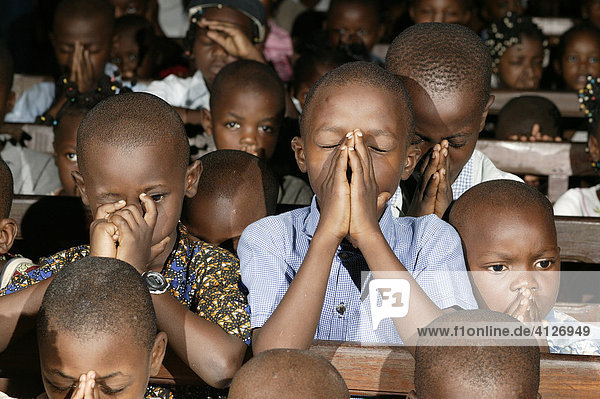 Children kneeling and praying in the pews during a wedding in Douala  Cameroon  Africa