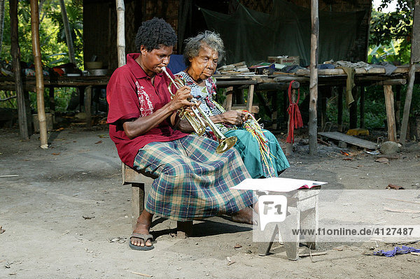 Trumpet player sitting next to an old woman  Heldsbach  Papua New Guinea  Melanesia
