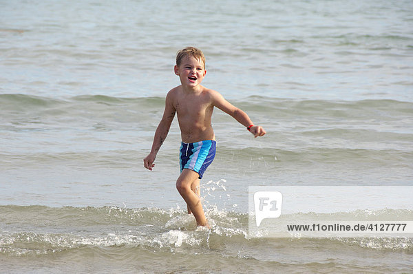 Boy running on the beach through the water  Caorle  Veneto  Italy