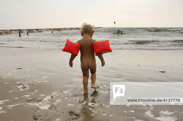Kleiner Junge mit Schwimmflügeln läuft am Strand entlang  Caorle  Venezien  Italien