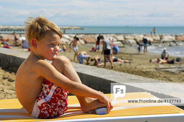 Junge sitzt auf einer Liege am Strand  Caorle  Venezien  Italien