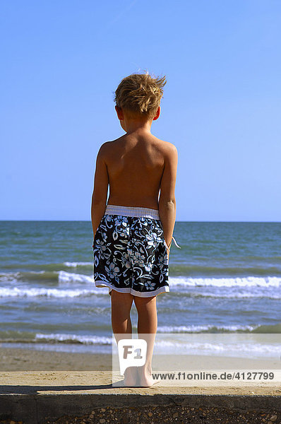 Junge steht am Strand und schaut aufs Meer  Caorle  Venezien  Italien