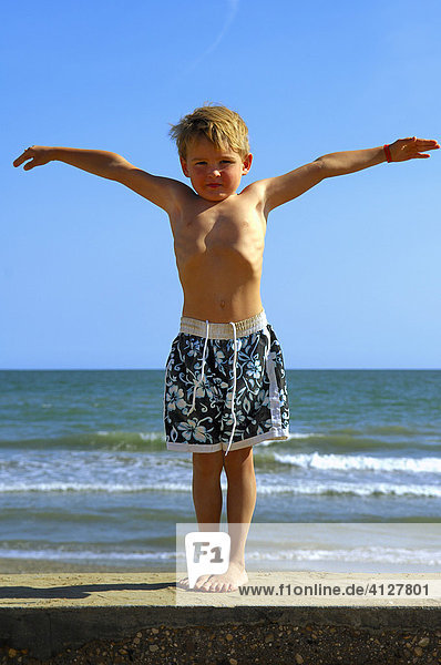 Junge steht am Strand und breitet die Arme aus  Caorle  Venezien  Italien