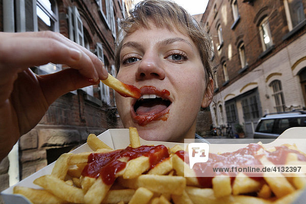 Young woman eats french fries with ketchup