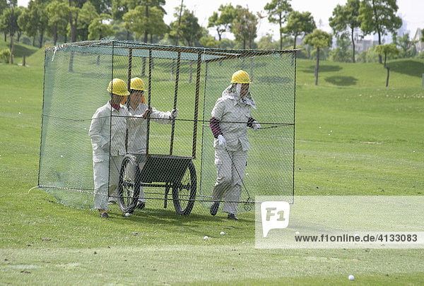 Frauen im Kaefig gehen ueber Driving Range und sammeln Golfbaelle auf  BMW Asian Open 2004  Tomson Golf Club  Shanghai  China