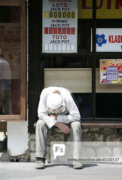 Alter Mann sitzt auf Bank vor Lotto Geschaeft  Sarajevo  Bosnien und Herzegovina