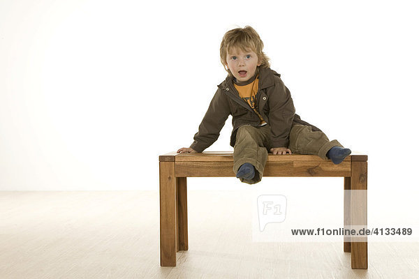 Junge  zweijährig  sitzt auf einer Bank