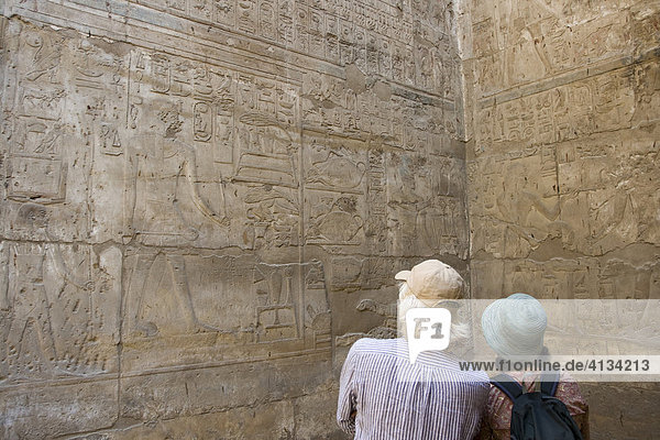 Two tourists looking at the hieroglyphs in the Amun Temple  Luxor Temple  Luxor  Nile Valley  Egypt  Africa