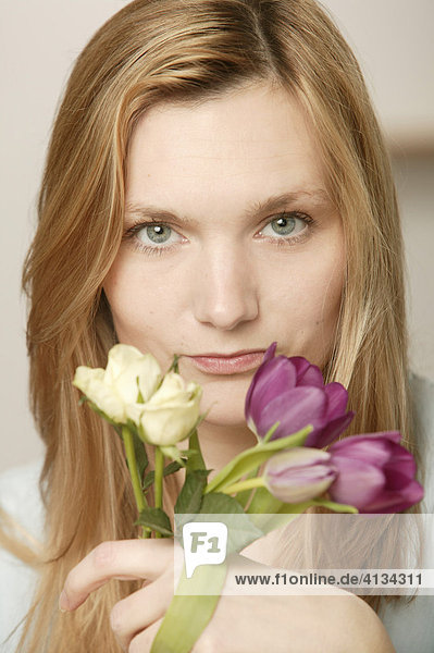 Junge blonde Frau mit Blumen  hellen und dunklen Tulpen