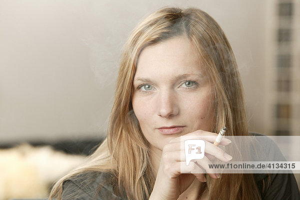 Junge blonde Frau raucht Zigarette mit viel Qualm