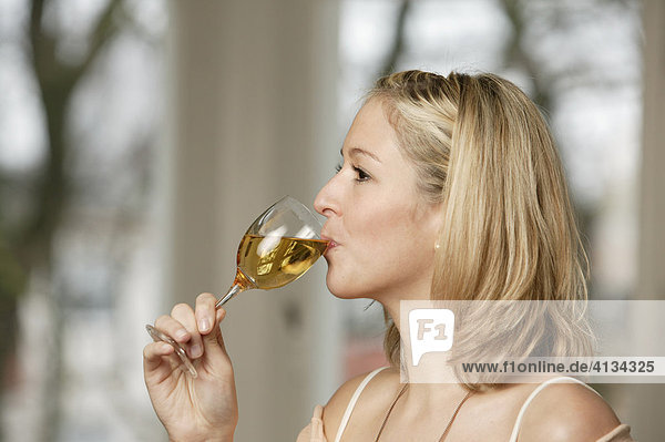 Young blonde woman drinking a glass of white wine