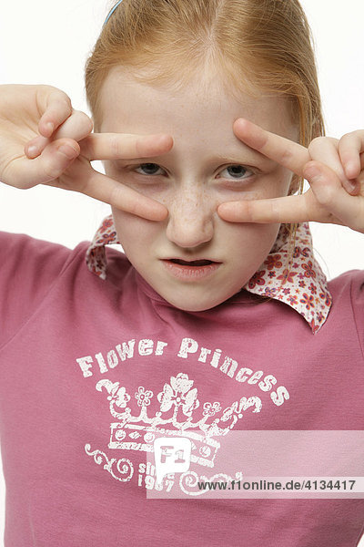 8-jähriges Mädchen mit Fingern vor dem Gesicht