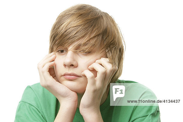 13-jähriger Junge im grünen T-Shirt  stützt den Kopf auf die Hände