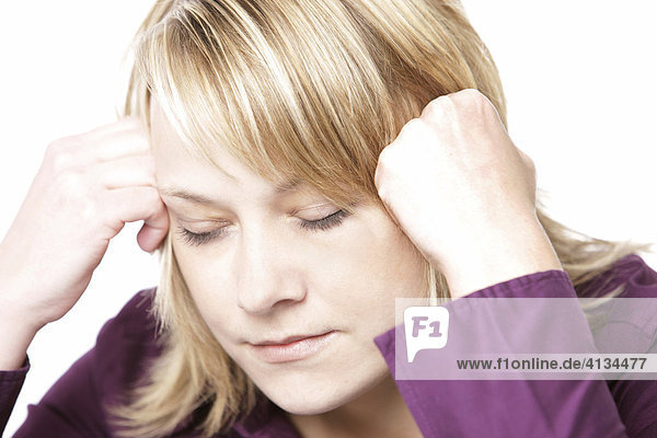 Blonde woman wearing a purple shirt  head leaning on her hands  eyes closed