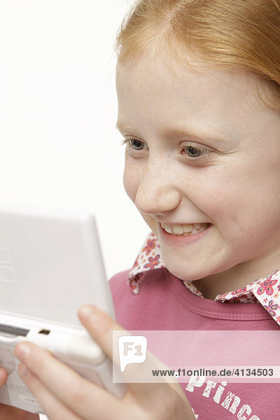 8-jähriges Mädchen mit roten Haaren spielt Game-Boy