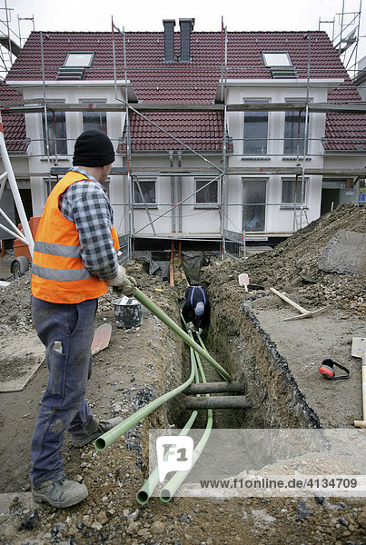 Tiefbauarbeiten  Arbeiter verlegen Anschlussrohre zu einem Wohnhaus  Essen  Nordrhein-Westfalen  Deutschland