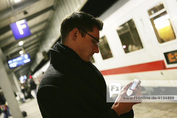 DEU Bundesrepublik Deutschland Mann mit Handy auf einem Bahnhof.