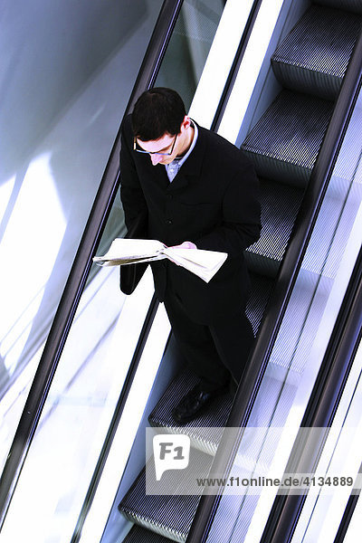 DEU Bundesrepublik Deutschland : Mann fährt auf einer Rolltreppe liest eine Tageszeitung.