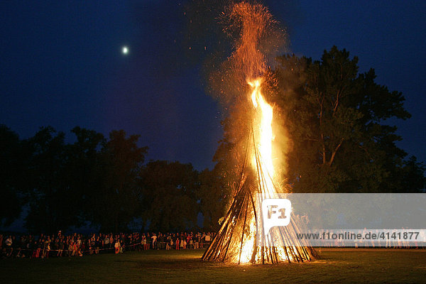 Midsummer bonfire against a night sky  moon