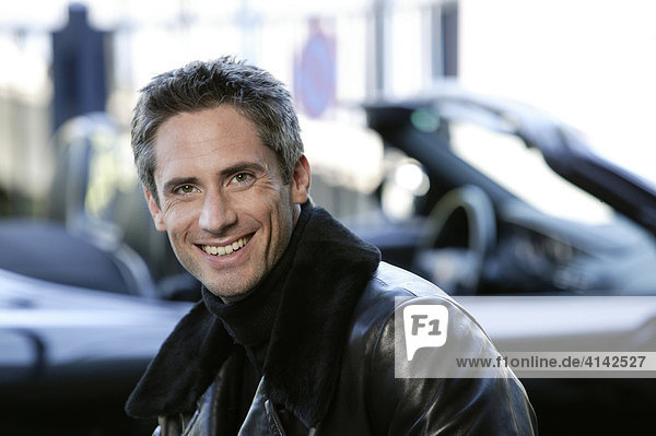 Man in leather jacket in front of his sports car