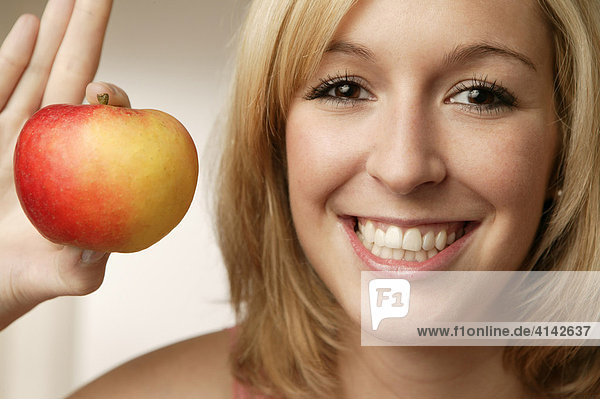 Junge  blonde Frau mit Apfel  lächelt  Nahaufahme