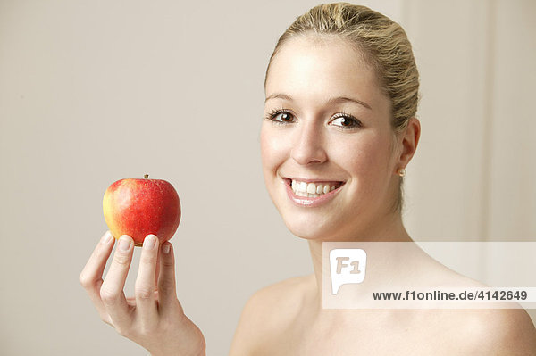 Junge  blonde Frau  mit Apfel  lächelt.