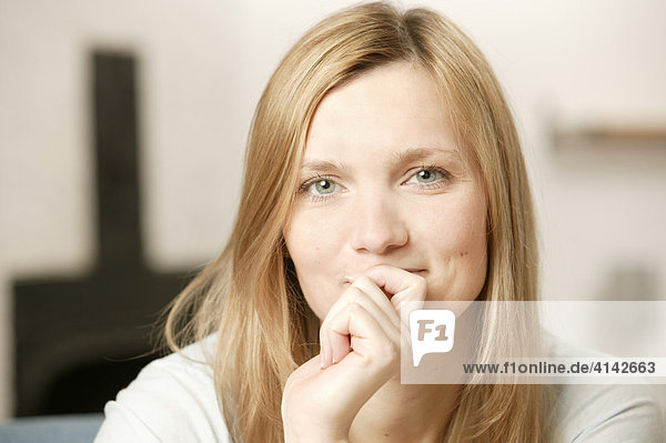 Blonde Frau lächelt  hält eine Hand vor den Mund