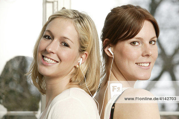 Zwei junge Frauen hören Musik mit einem Paar Ohrhörer