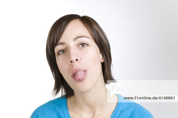 Junge Frau streckt die Zunge heraus
