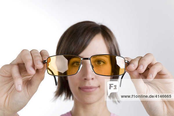 Junge Frau schaut durch eine Sonnenbrille